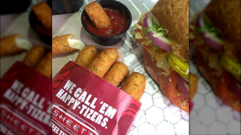 A package of Sheetz mozzarella sticks on a table next to a cup of marinara sauce