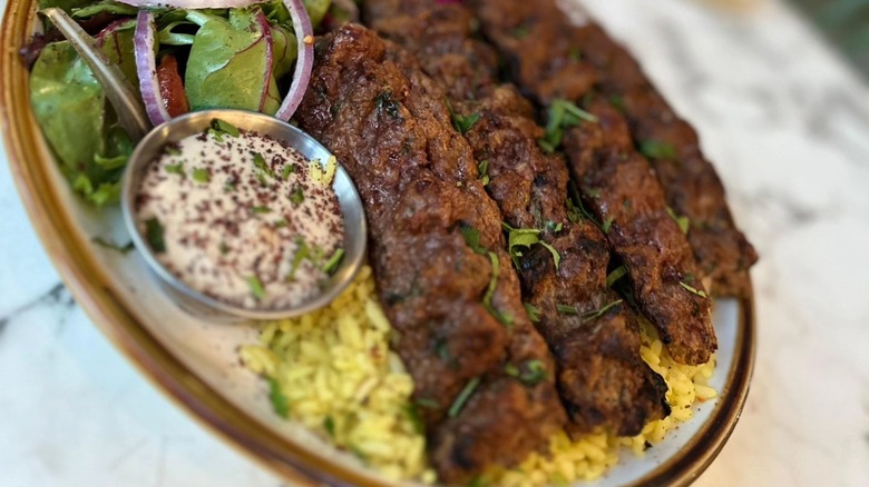 Kabobs on rice with dip and salad on side