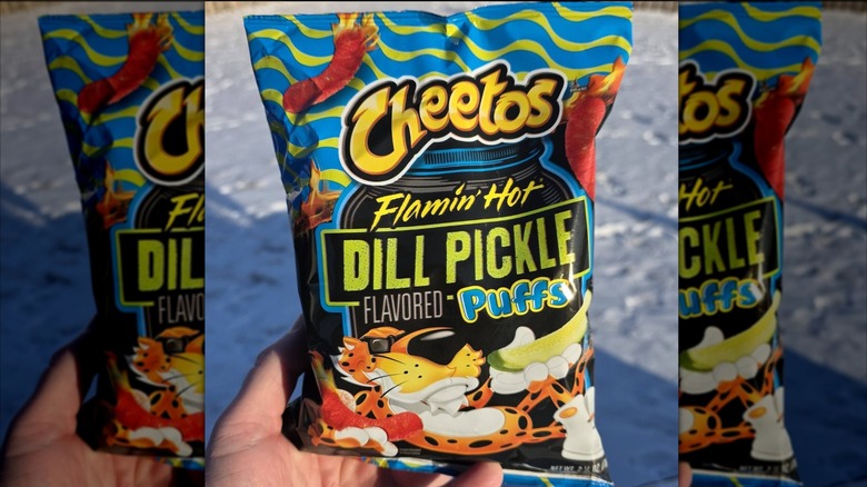 Hand holding Cheetos Flamin Hot Dill Pickle puffs