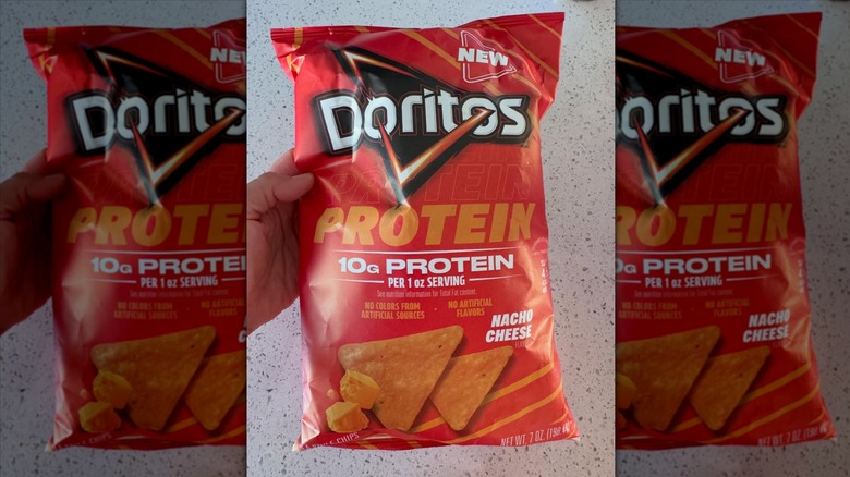 Hand holding Doritos protein chips bag