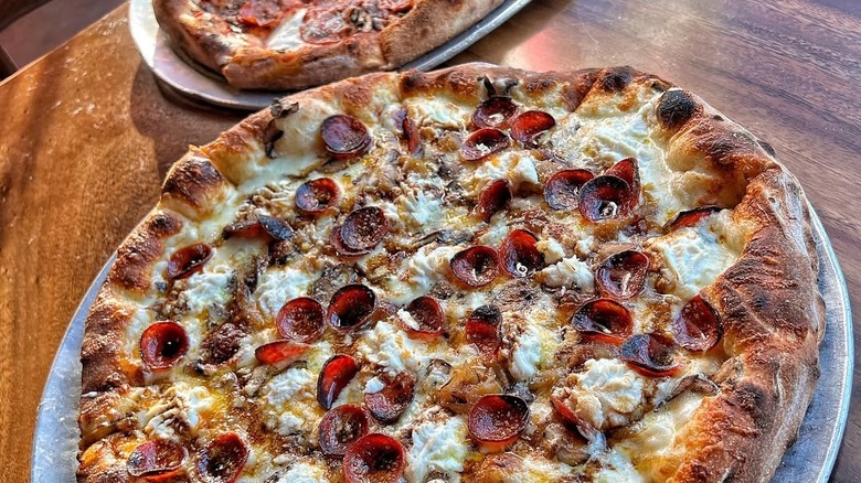 Two pizzas on wood table