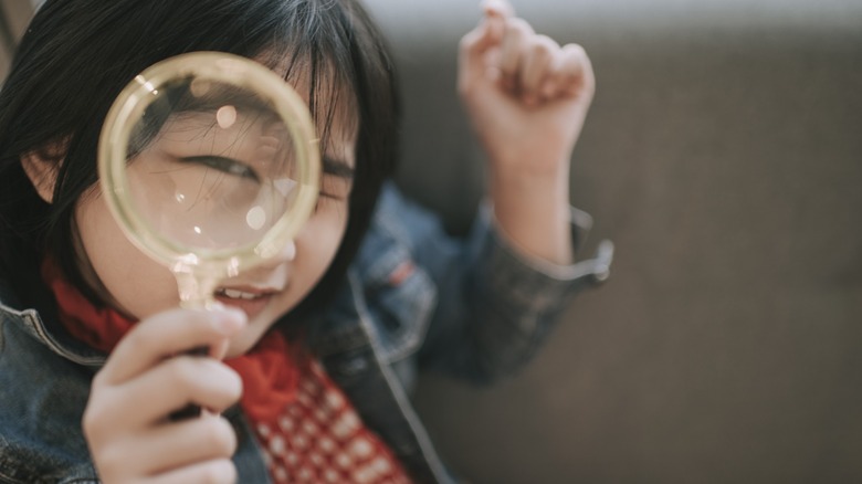 asian chinese girl looking through magnify glass with funny face