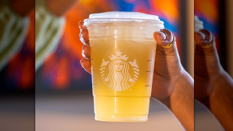A hand holds a Starbucks iced green tea