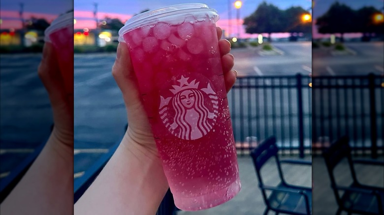 A hand holds an Iced Passion Tango tea from Starbucks