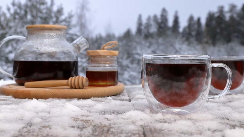 coffee pot, cups of coffee, and jar of honey sitting in the snow