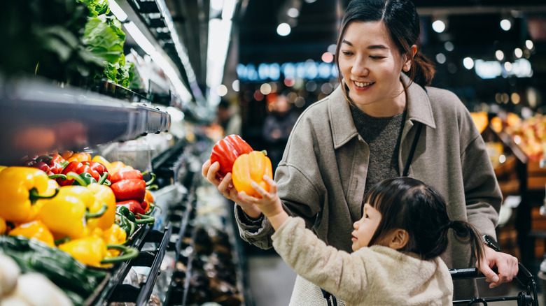 A parent and child shopping for vegetables