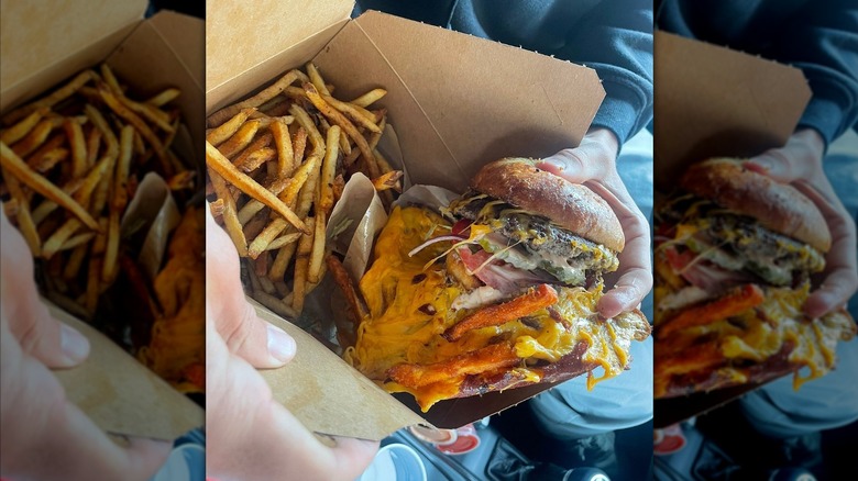 Hand lifting Hangover burger out of box with fries