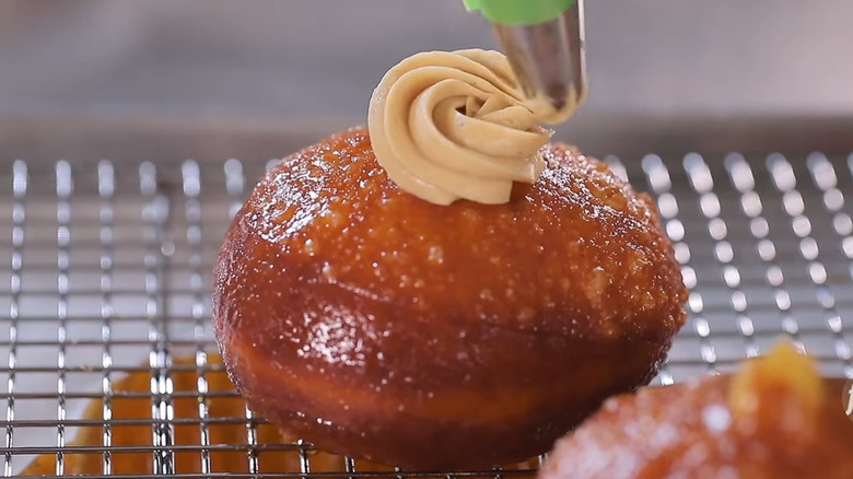 Rum baba donut being piped with cream