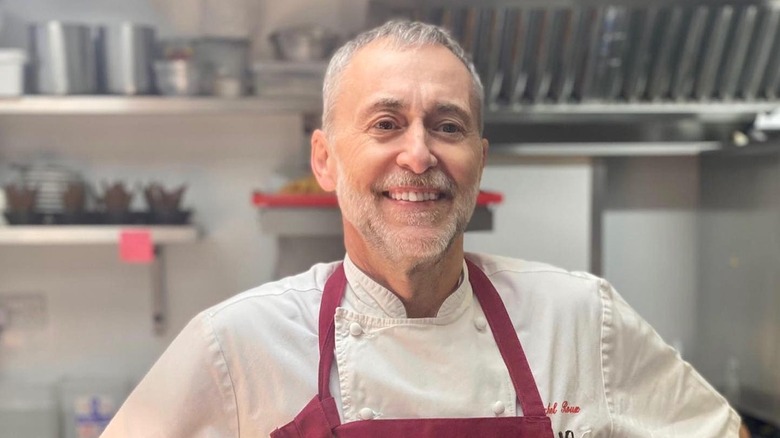Close up of chef Michel Roux Jr in the kitchen wearing a red apron