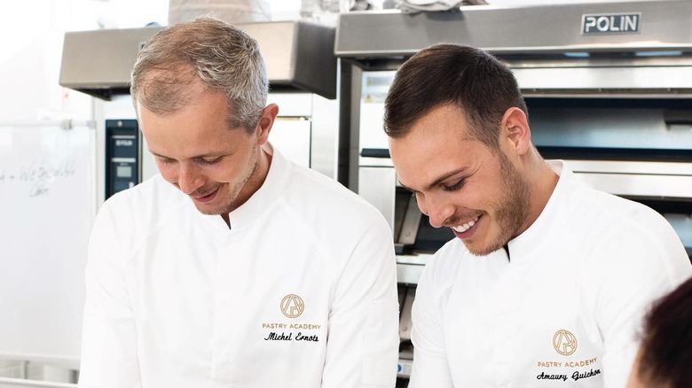 Chef Amaury Guichon and Chef Michel smiling and working in the kitchen