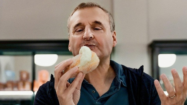 Phil Rosenthal happily eating a sweet bun