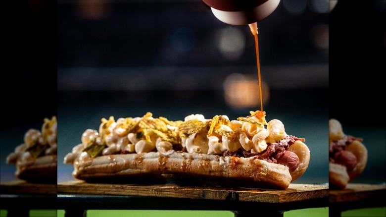 Sauce being squeezed from a bottle onto a Daddy Mac Dog