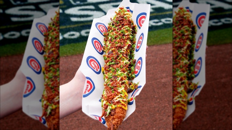 A hand holding a Korean Corn Dog at the edge of a football field