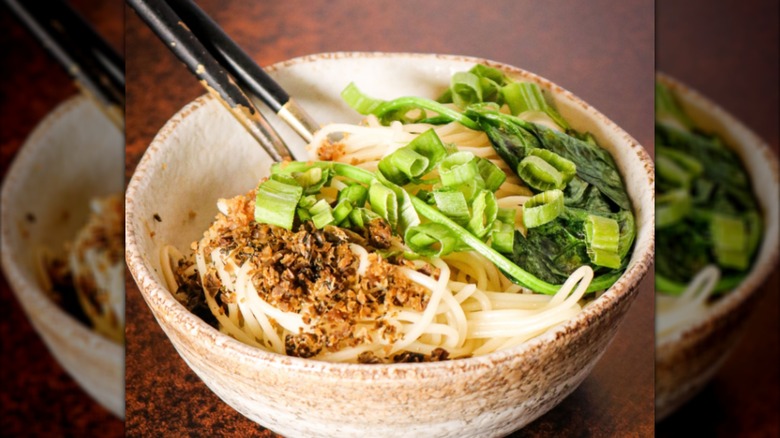 A bowl of noodles and toppings sitting on a dark surface.