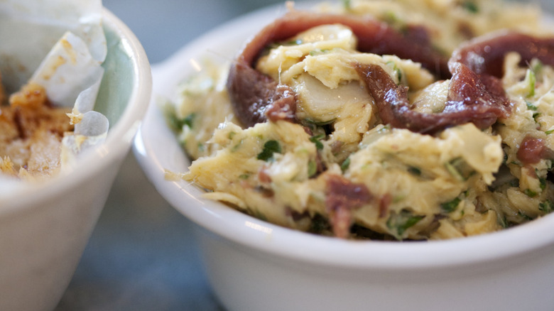 A small dish of butter flavored with parsley and anchovies