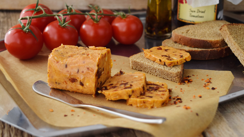 Homemade butter made with sun-dried tomatoes alongside fresh tomatoes and bread