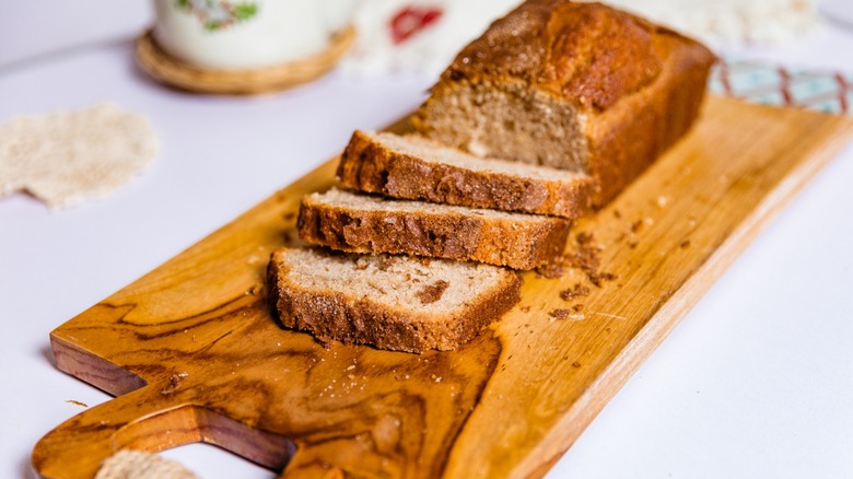 Loaf of Amish friendship bread with three slices cut on wooden cutting board