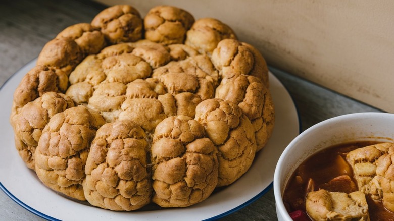 Fluffly, golden, Indigenous frybread on white plate next to bowl of ingredients