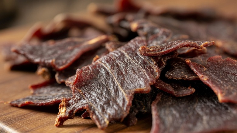 Pile of beef jerky strips on wooden surface