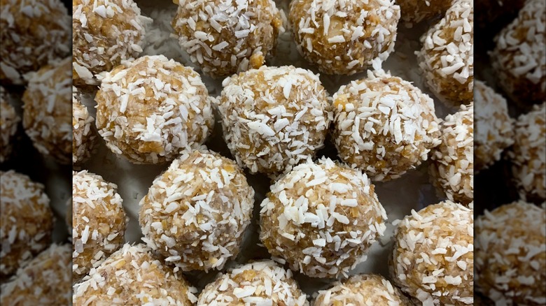 Rows of homemade peanut butter balls rolled in coconut flakes