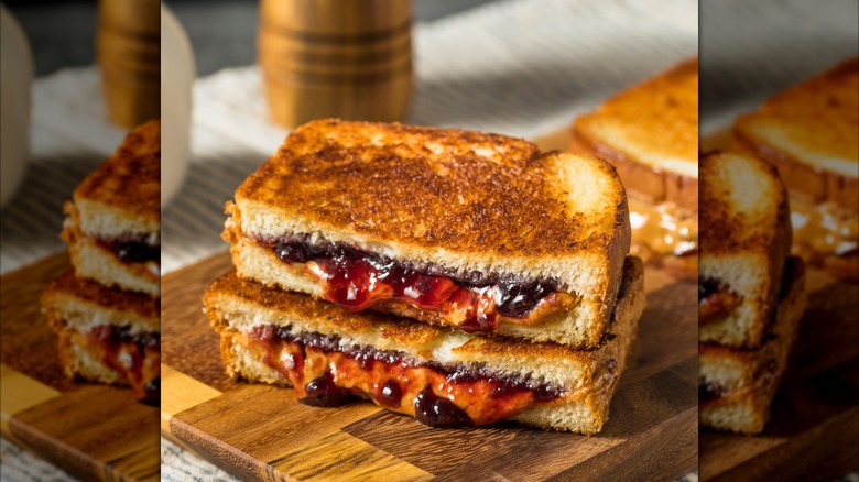 Grilled PB & J sandwich cut in half on wooden cutting board