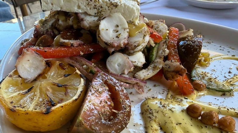 A plate holding grilled fruit, vegetables, cheese, and sauces.