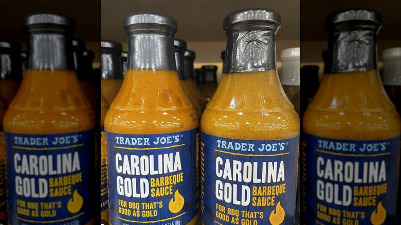 Glass bottles of Trader Joe's Carolina Gold Barbecue Sauce in rows on store shelf