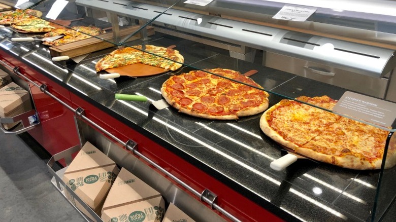Whole Foods pizza counter with various types of round pizzas