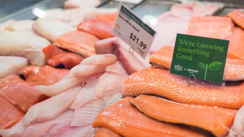 Salmon and other fish fillets on a seafood counter with Whole Foods signage