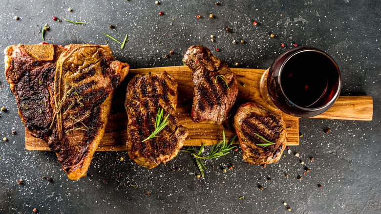 Top view of four grilled steaks on a wooden cutting board