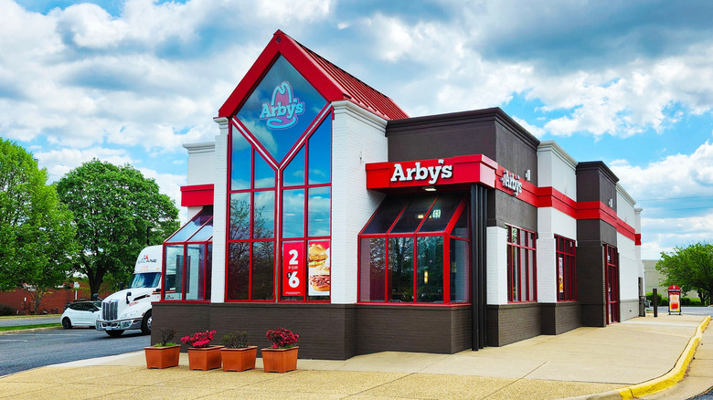 Arby's fast food restaurant exterior with red, white, and gray facade, a drive-thru, and nearly empty parking lot