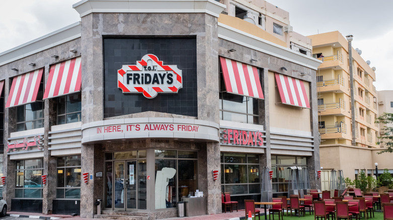 TGI Fridays restaurant exterior with red and white striped awnings and a seating area outside