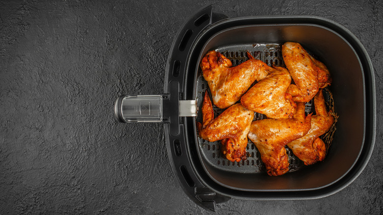 Top view of crispy golden chicken wings freshly cooked in an air fryer basket