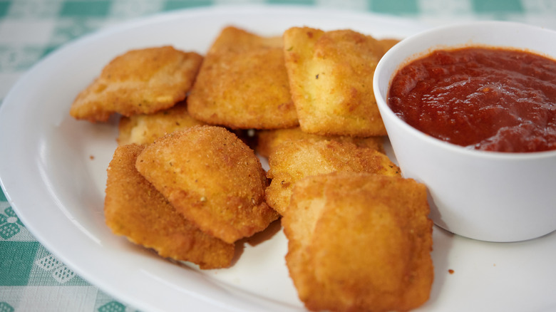 Fried ravioli on white plate on the table with marinara sauce