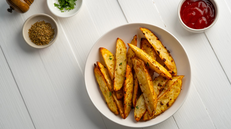 Air Fryer Roast Potatoes on white plate,potato wedges with tomatoes sauce.