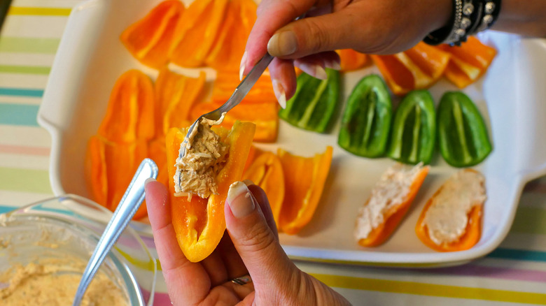 Preparation of Sweet pepper poppers: mini yellow peppers stuffed with cheese and sopasco spice, then rolled in smoked bacon