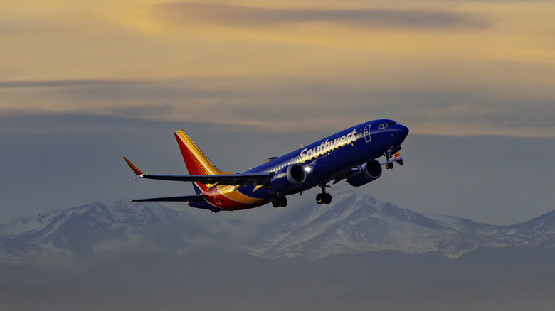 A Southwest plane takes off from Denver International Airport with rocky mountains in background