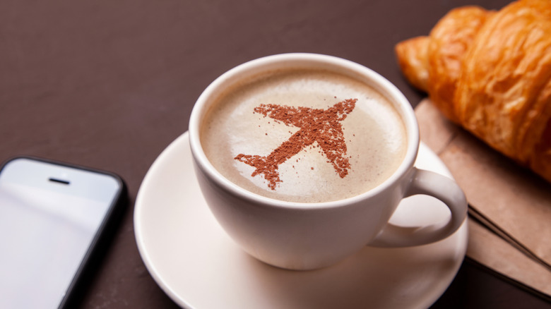 Latte with a cocoa-dusted airplane design on top of foam