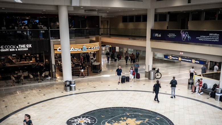 Travelers walking around a Caribou Coffee location inside one of the main halls of Minneapolis Saint Paul airport