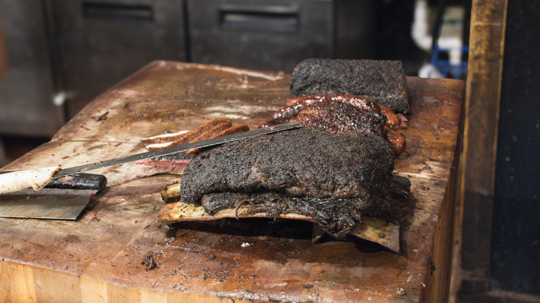 Briskets and sausages on wood cutting stand