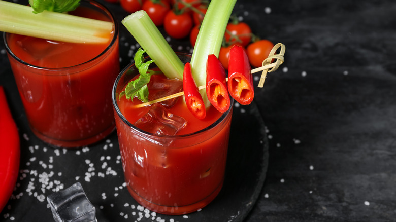A bloody mary garnished with celery and red peppers on a bar.