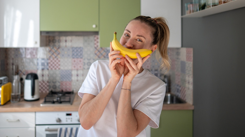 woman holding a banana up to her mouth as a smile