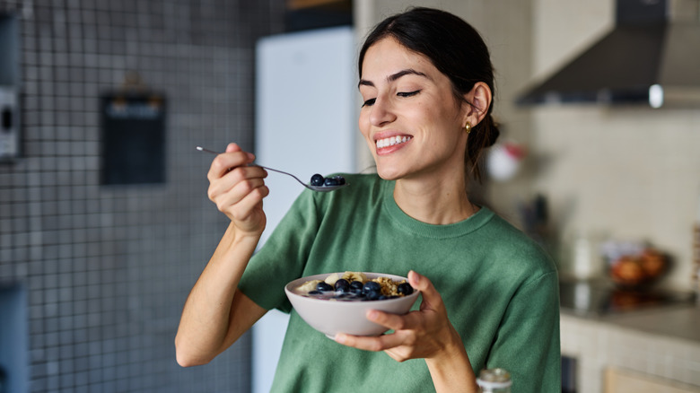 A woman eating blueberries and cereal
