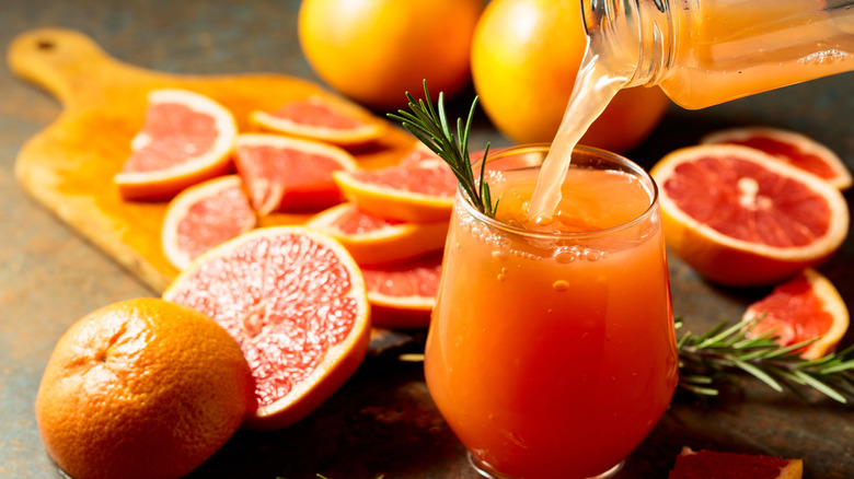 grapefruit juice being poured into a glass, surrounded by grapefruit slices