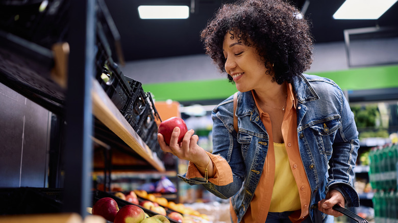 A woman shopping for apples in a grocery store
