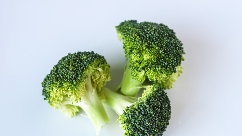 A close-up of three pieces of fresh broccoli