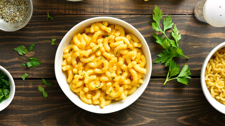 Homemade macaroni and cheese in white bowl on wooden background