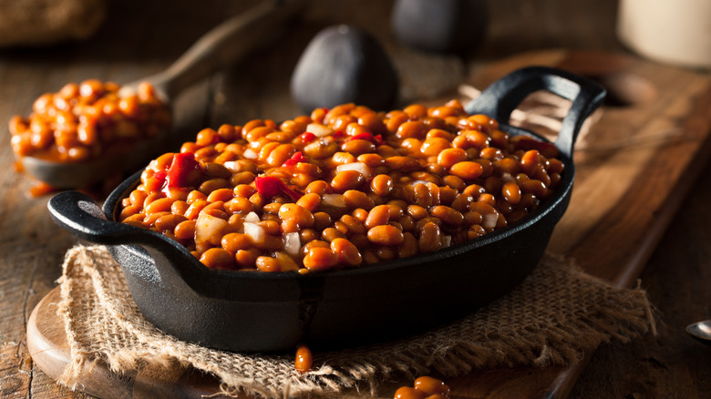 Homemade baked beans in a black skillet resting on burlap