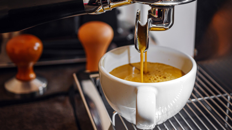 An espresso machine brewing and pouring a cup of espresso into a white mug.