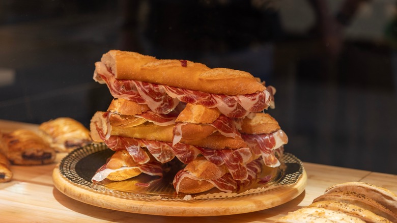 Traditional Spanish sandwich with cured Serrano ham on crusty bread, a classic lunch snack or tapas (bocadillo de jamon serrano), Spain. Iconic Mediterranean street food
